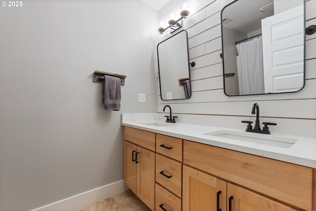 full bath with a sink, baseboards, tile patterned floors, and double vanity