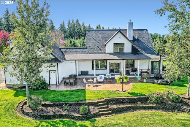 back of house featuring a lawn, a chimney, and a patio area