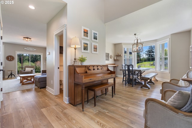 living room featuring baseboards, recessed lighting, light wood-style flooring, and a notable chandelier