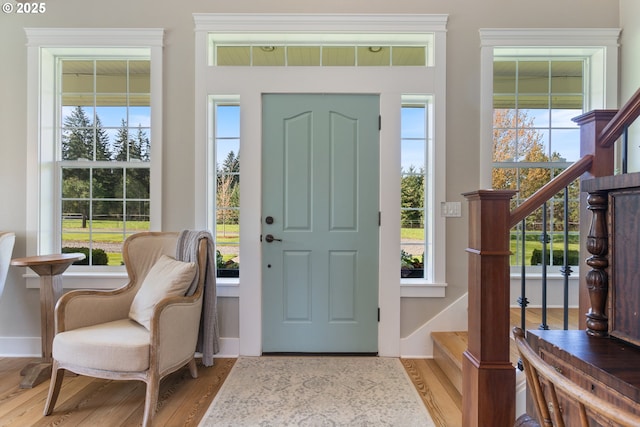 foyer with baseboards, plenty of natural light, wood finished floors, and stairway