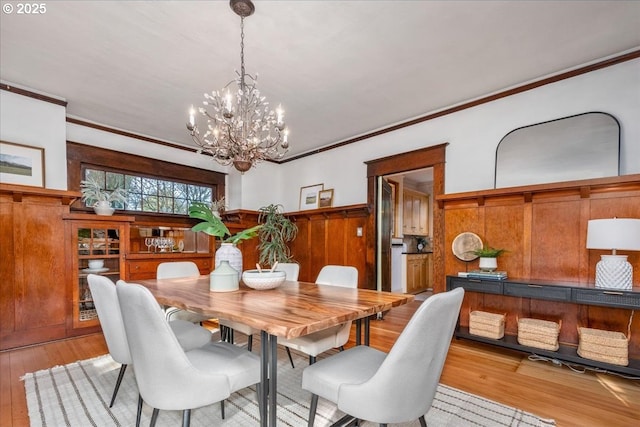 dining space featuring crown molding, an inviting chandelier, and light wood-type flooring