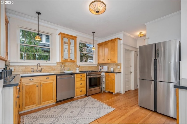 kitchen featuring appliances with stainless steel finishes, decorative light fixtures, sink, backsplash, and light hardwood / wood-style floors