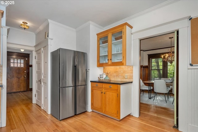 kitchen featuring backsplash, stainless steel fridge, a notable chandelier, crown molding, and light wood-type flooring