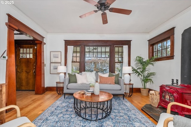 sitting room with ornamental molding, wood-type flooring, and a wood stove