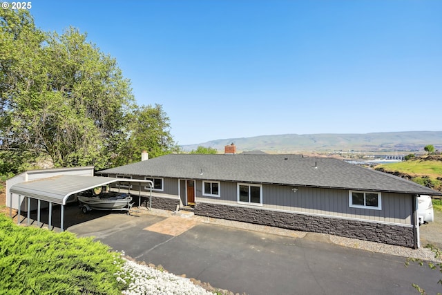 ranch-style home featuring stone siding, a detached carport, aphalt driveway, and a mountain view