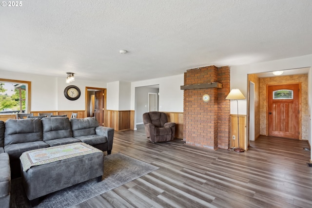 living area with a wainscoted wall, a textured ceiling, wooden walls, and wood finished floors