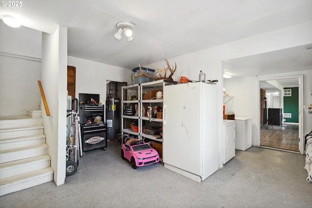 storage room with washer and clothes dryer, electric water heater, and visible vents