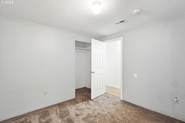 unfurnished bedroom featuring carpet, visible vents, and a closet