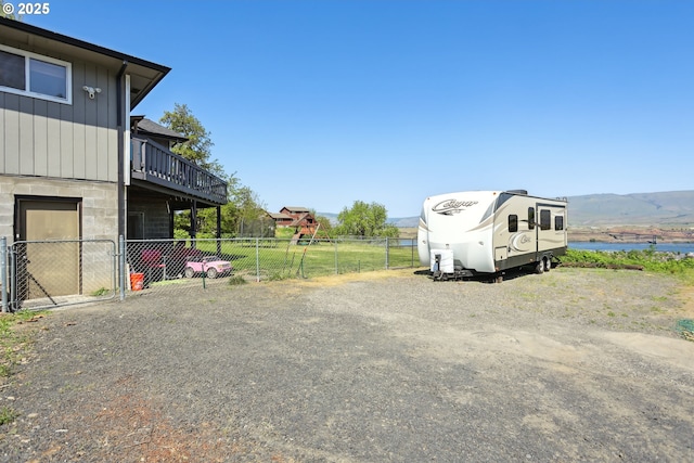 view of parking / parking lot with fence and a water view