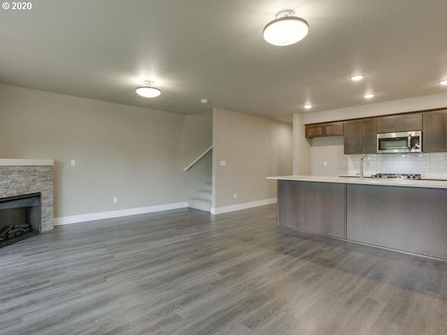 kitchen with light wood-style flooring, stainless steel microwave, light countertops, and open floor plan