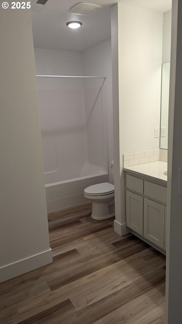 full bath featuring toilet, shower / bath combination, wood finished floors, and vanity