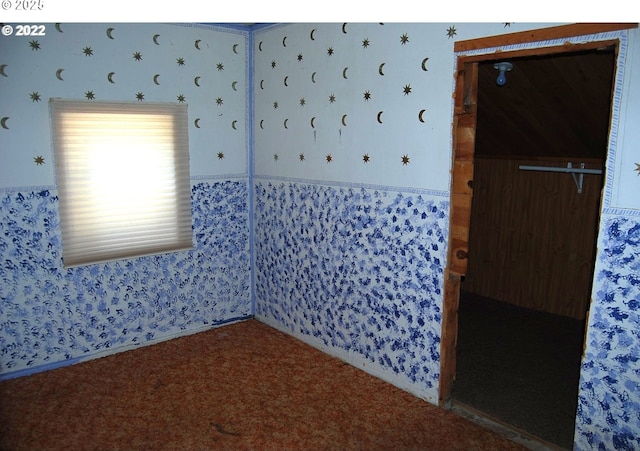 carpeted empty room featuring wallpapered walls
