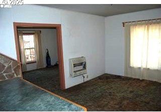 empty room with heating unit and carpet floors