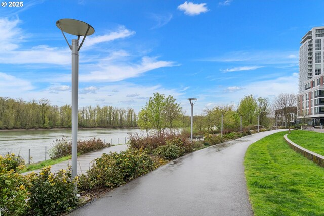 surrounding community with a water view and a lawn