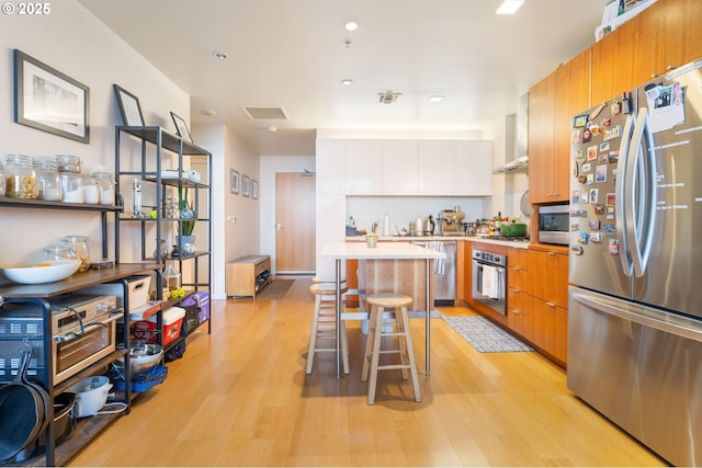 kitchen featuring light countertops, modern cabinets, light wood-style flooring, and appliances with stainless steel finishes