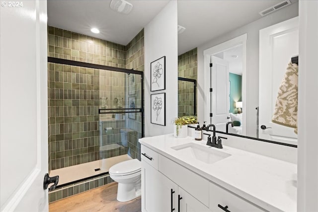 bathroom with hardwood / wood-style floors, vanity, a shower with shower door, and toilet