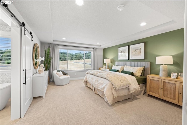 carpeted bedroom with a barn door and a textured ceiling