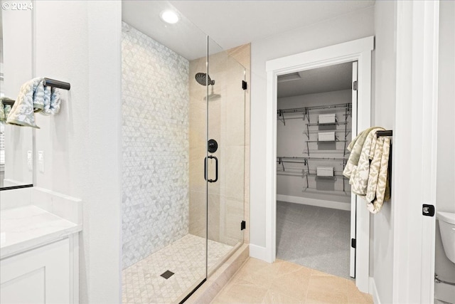 bathroom featuring tile patterned floors, vanity, toilet, and a shower with door