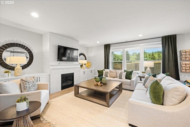 living room featuring light hardwood / wood-style flooring and a tiled fireplace