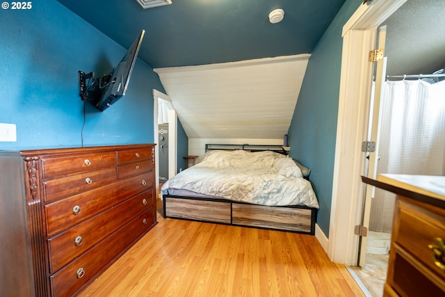 bedroom with wood finished floors and vaulted ceiling