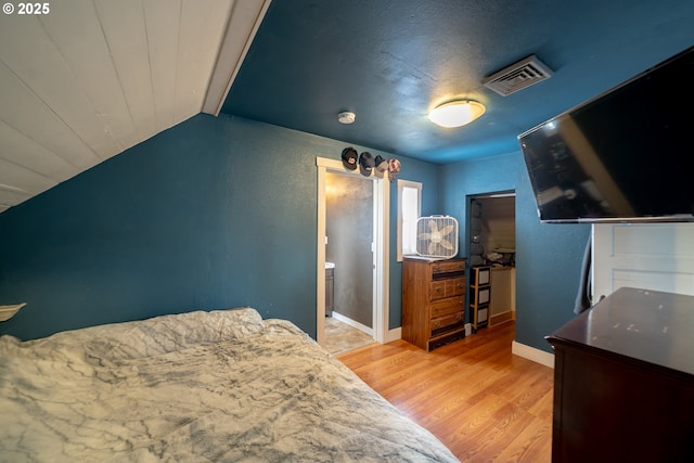 bedroom with light wood-style flooring, lofted ceiling, and baseboards