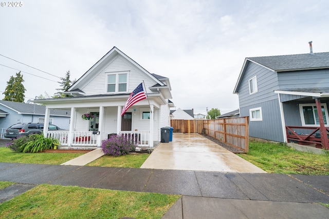view of front of home featuring a porch, concrete driveway, and fence
