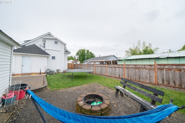 view of patio / terrace with an outdoor fire pit, a trampoline, and central AC