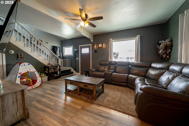 living area featuring stairs, wood finished floors, ceiling fan, and beam ceiling