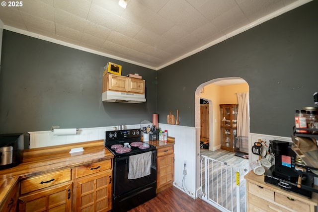 kitchen with black electric range oven, under cabinet range hood, ornamental molding, arched walkways, and dark wood-style flooring