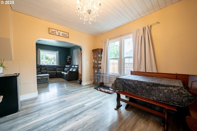 bedroom featuring arched walkways, wood finished floors, a chandelier, wood ceiling, and baseboards