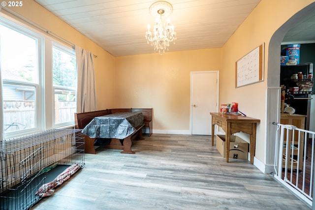 bedroom with arched walkways, wood finished floors, and a chandelier