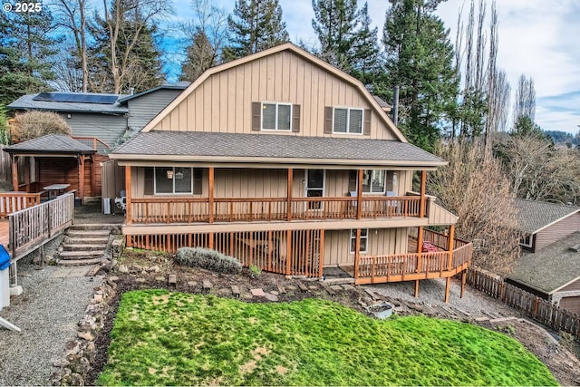 back of house with board and batten siding, a shingled roof, fence, and a porch