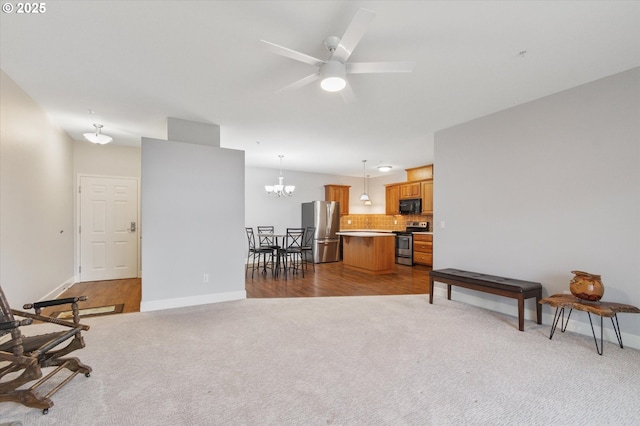 sitting room with ceiling fan with notable chandelier and carpet floors