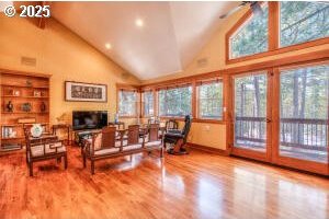 living area with high vaulted ceiling and wood finished floors