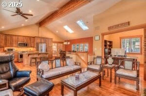 living room featuring a ceiling fan, beam ceiling, high vaulted ceiling, and wood finished floors