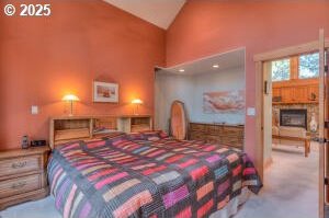 carpeted bedroom with high vaulted ceiling and a fireplace