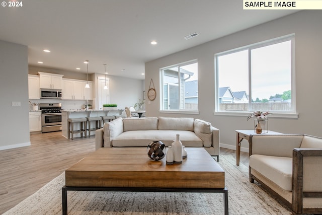 living area featuring recessed lighting, visible vents, baseboards, and light wood-style flooring