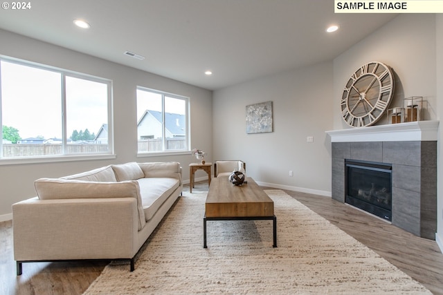 living area with recessed lighting, wood finished floors, visible vents, and a tile fireplace