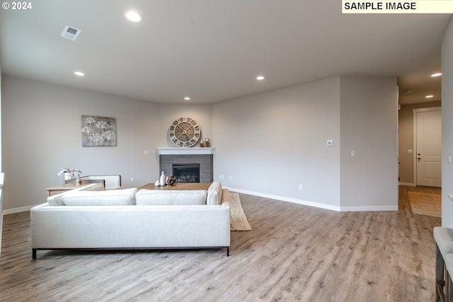 living area with visible vents, a tiled fireplace, wood finished floors, recessed lighting, and baseboards