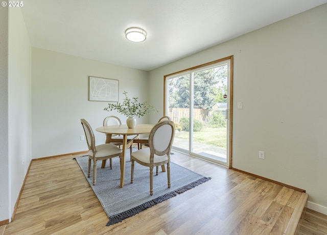 dining space with baseboards and light wood-style flooring