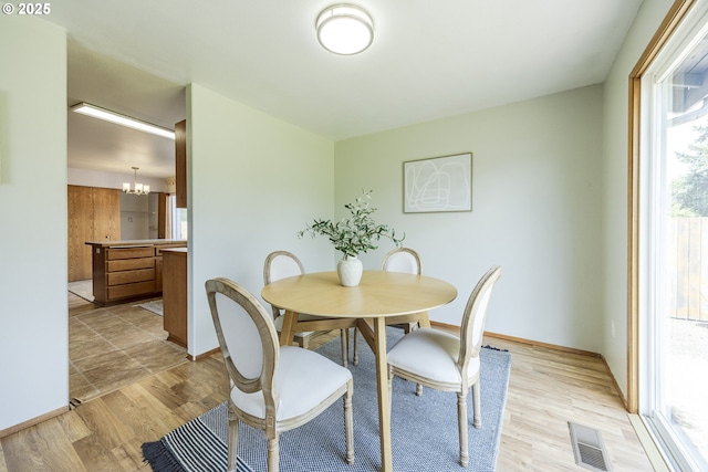 dining room featuring visible vents, light wood finished floors, baseboards, and a chandelier