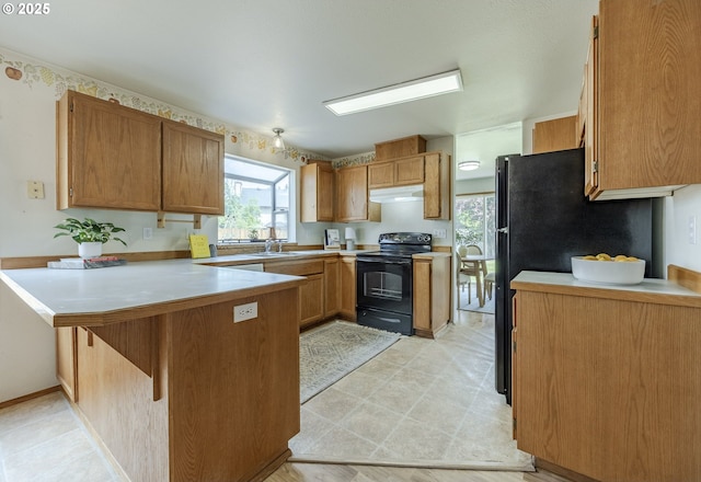 kitchen featuring a peninsula, light countertops, under cabinet range hood, a sink, and black / electric stove