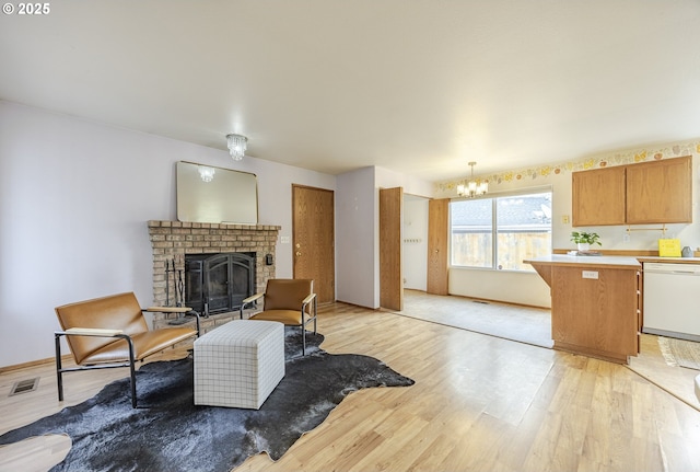 living area with visible vents, a fireplace, light wood finished floors, and a chandelier