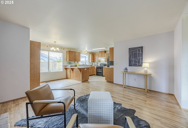 living area featuring baseboards, light wood-style flooring, and a chandelier