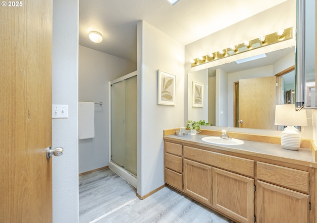 full bath with vanity, baseboards, wood finished floors, and a shower stall