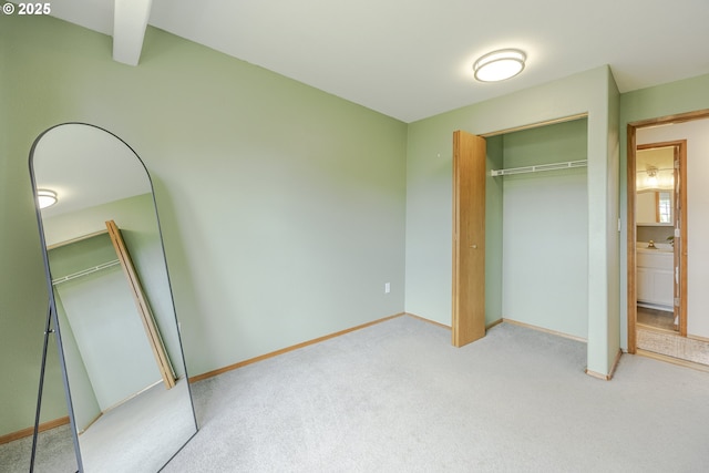 unfurnished bedroom featuring baseboards, light carpet, and a closet