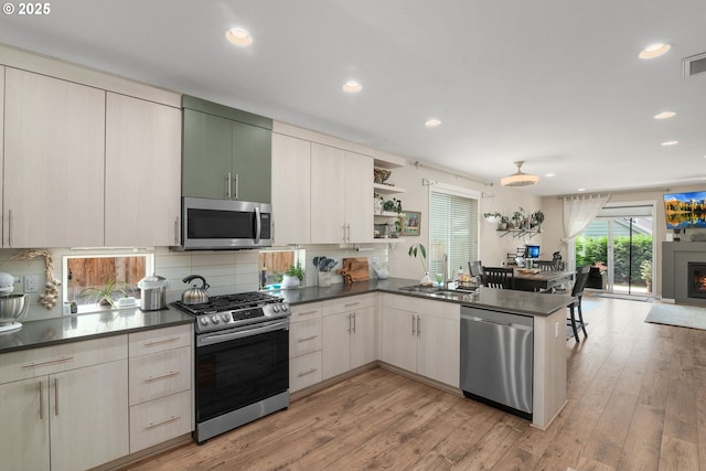 6910 SE Lamphier St, Milwaukie, OR 97222 - kitchen featuring stainless steel appliances, dark countertops, a peninsula, a sink, and backsplash