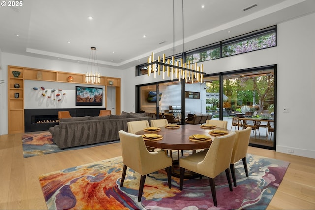 1235 Andrews Rd, Lake Oswego, OR 97034 - dining area with a chandelier, a raised ceiling, light wood-style flooring, recessed lighting, and a lit fireplace