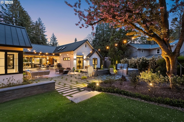 1235 Andrews Rd, Lake Oswego, OR 97034 - back of house at dusk with an outdoor living space, a standing seam roof, a patio, a metal roof, and a yard