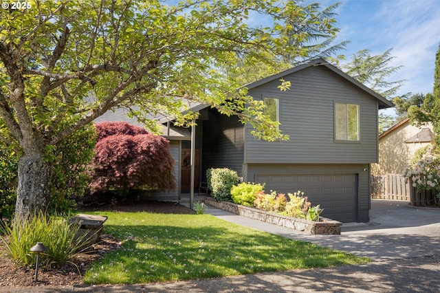 split level home with an attached garage, fence, driveway, and a front yard